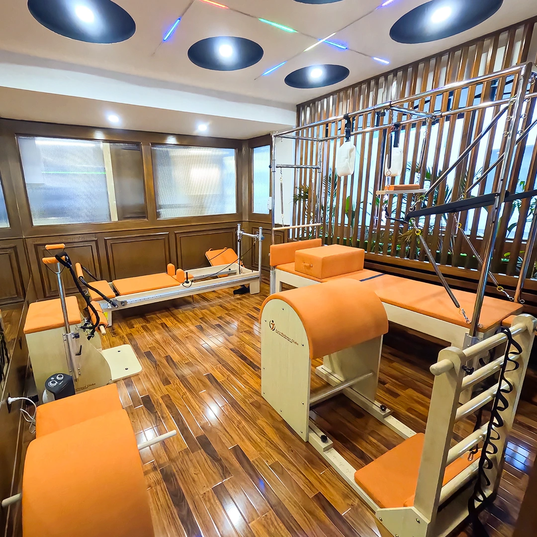 An expansive view of the dedicated Pilates zone featuring multiple custom reformers. The warm wood flooring and integrated ceiling lighting create a focused, high-end atmosphere for core-centric training